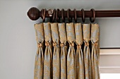 Dark wood curtain pole and gathered curtain with decorative metal buttons