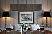 Wooden table and upholstered chairs in rustic dining room with white wood-panelled walls