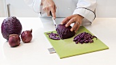 A chef cutting red cabbage on a chopping board