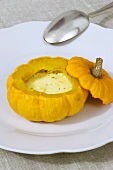 A hollowed out Jack-Be-Little pumpkin filled with melted cheese