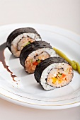 Drei Maki-Sushi mit Sojasauce und Wasabi