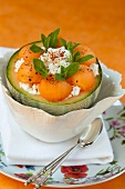 Melon dessert served in a hollowed out melon with cottage cheese and mint