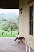 Schlichte Bank auf Terrasse vor Hauswand und Blick auf die Berge