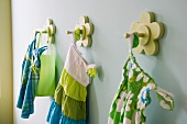 Blau und grün gemusterte Kinderkleidchen an blütenförmigen Wandhaken