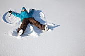 Woman making snow angel on field