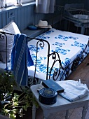Metal bed with a bedspread decorated with a blue and white pattern