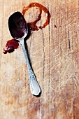 The remains of fruit sauce on a spoon and on a chopping board