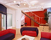 Colourful, upholstered sofa set in loft-style interior with staircase