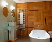 Free-standing bathtub in front of wood-panelled wall in designer bathroom