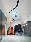 Grosses Treppenhaus mit beleuchteter Holztreppe in modernem Gebäude