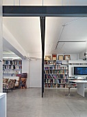 Minimalistischer, offener Wohnraum mit großer Bücherwand