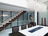 Modern dining room with beaded crystal chandelier and staircase