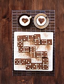 Domino tiles made of brownies, and two cups of cappuccino