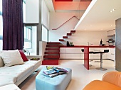 Farbige Polstermöbel und offene Küche im modernen Wohnraum mit Treppenaufgang