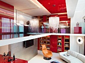 Blick von Galerie auf modernen Kronleuchter an roter Decke und in Wohnraum mit Polstercouch