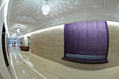 Polierte Steinfliesen an Wand und Boden und eingebaute Sitzbank mit lila Samtbezug in modernem Vorraum