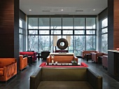 Clubatmosphäre - Tische und Polstersitzmöbel im Raum mit Glasfassade in zeitgenössischer Architektur