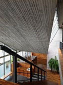 Blick auf Treppe aus Holz in die Halle mit Sichtbetondecke