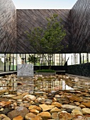 Wasserbassin mit Felsbrocken auf Boden im Innenhof einer zeitgenössischen Architektur