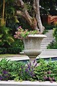 Antik griechische Vase im Blumenbeet und Blick auf Pool und Treppenanlage im Garten