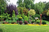 Große Pflanzenvielfalt in eleganter Gartenanlage mit kunstvoll geschnittenen Pflanzen und gepflegtem Rasen