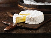 Camembert, angeschnitten, auf Schneidebrett