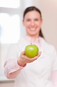 Smiling doctor offering green apple