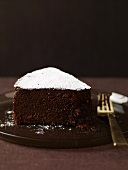 A slice of chocolate cake with icing sugar