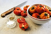 Tomaten, ganz & aufgeschnitten daneben Messer, Salz & Pfeffer