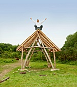 Man cheering on roof of log hut