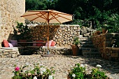 Eckbank und Terrasse aus Naturstein mit Sonnenschirm