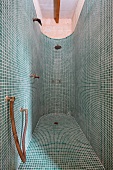Duschbereich mit abgerundeter Wand und grünen Mosaikfliesen