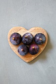 Five figs on a heart-shaped wooden plate