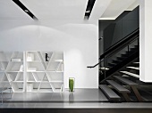 White bookshelves on a wall next to a staircase in an open living room