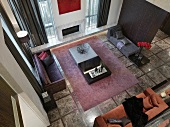 View of assorted upholstered furniture around a low table on a carpet in a minimalist living room on a gray stone floor