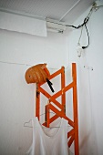 Vest and pumpkin helmet on red wooden lattice girder in corner of room