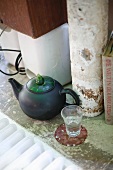 Black teapot with courgette lid and glass of water on sausage slice coaster