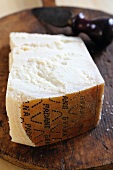 A piece of Grana Padano cheese on a chopping board