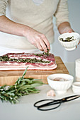 Pork being spread with herb stuffing ready to be rolled and roasted
