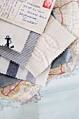 Fabric swatches in maritime styles and stamped postcard fanned out on top of map