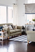 Light-flooded seating area with two sofas accessorised with blue and white cushions and woven rug