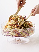 Hands Tossing Cole Slaw in a Serving Bowl