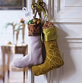 Baubles and presents in colourful Christmas stockings hanging on door handle of white interior door