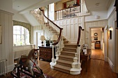 Antikes Schaukelpferd vor weiss lackierter Holztreppe in der grosszügigen Diele eines elegant gemütlichen Landhauses mit Parkettboden.