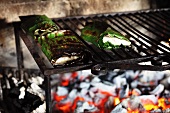 Sturgeon fillets wrapped in banana leaves on a wood-fired barbecue