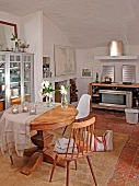 Round wooden table, simple kitchen chair and Bauhaus shell chair in Mediterranean dining room with kitchenette