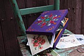 Collection of post cards in painted and decorated wooden box on vintage chair