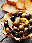 Verschiedene eingelegte Oliven in Schälchen mit geröstetem Brot