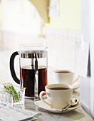 A Cup of Black Coffee Next to a French Press