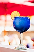 Margarita in einem blauen Glas mit Salzrand und Zitronenscheibe